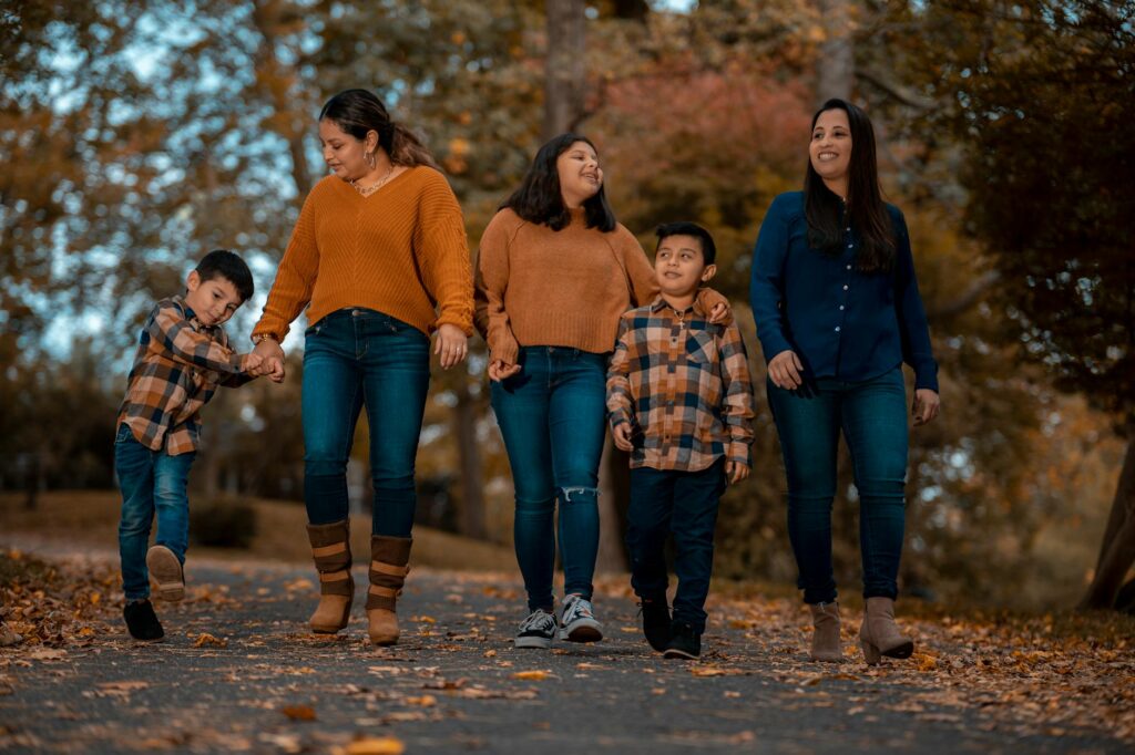 A family strolls through a park, enjoying the vibrant fall foliage.