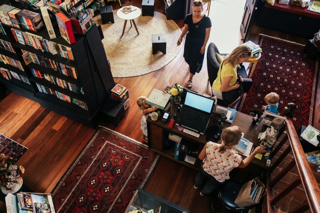 A vibrant bookstore scene with people browsing and interacting, showcasing bookshelves and unique rugs.