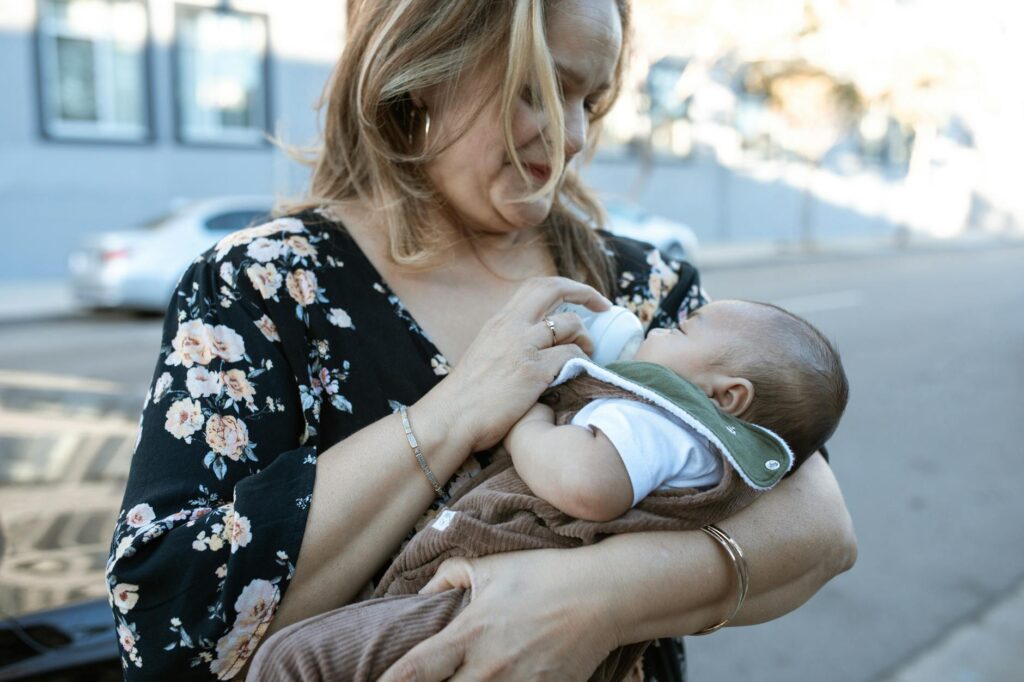 Capture of a mother feeding her baby with a bottle, showcasing tender motherhood moments.
