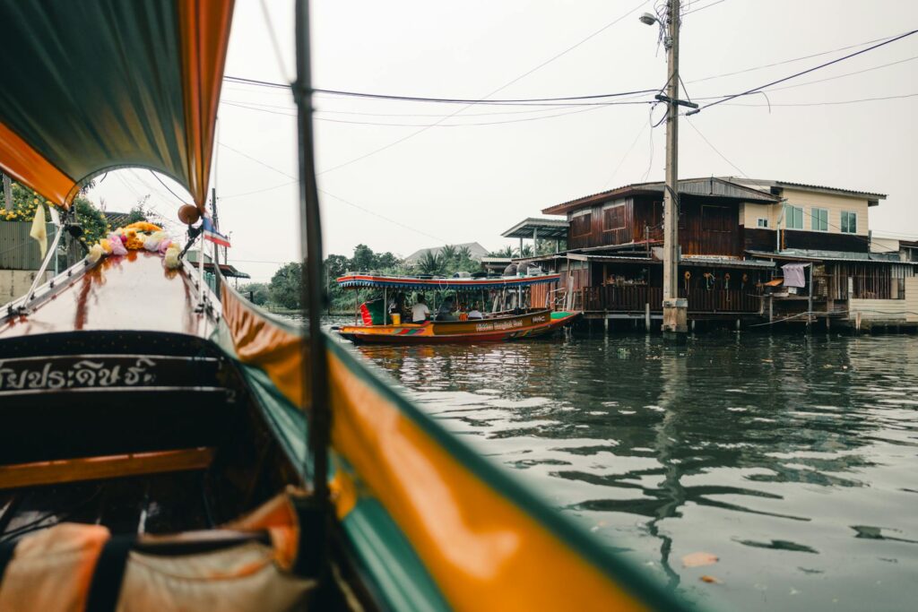 Experience a serene boat ride through Bangkok's rustic canals, capturing traditional Thai architecture.