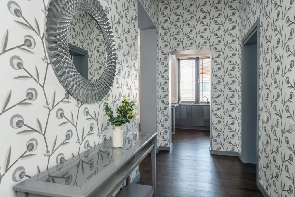 Contemporary hallway featuring decorative wallpaper, a mirror, and a table with flowers, creating an elegant atmosphere.