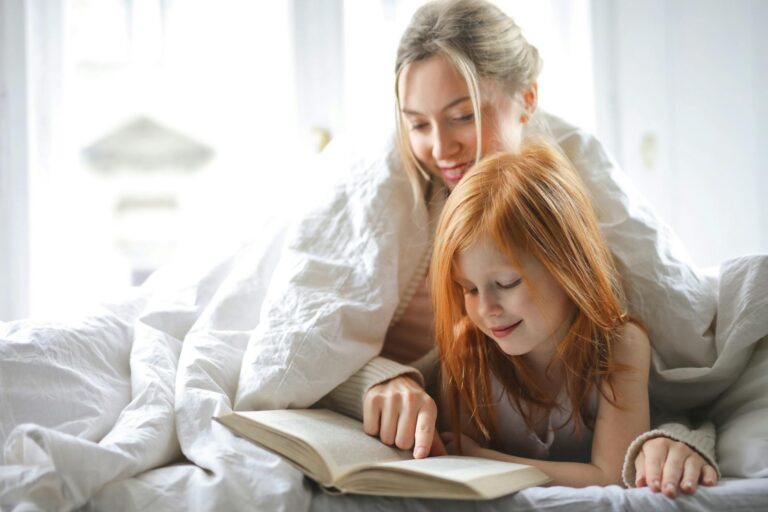Heartwarming scene of mother and daughter bonding while reading together in bed.