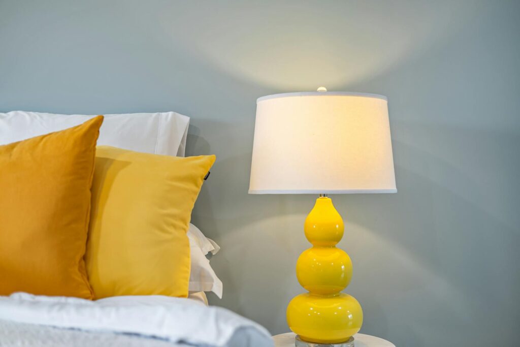 Cozy bedroom interior featuring yellow accents and a chic bedside lamp for a warm ambiance.