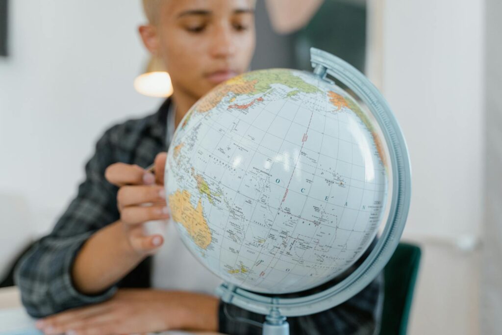 Close-up view of a person studying a globe indoors. Perfect for educational contexts.