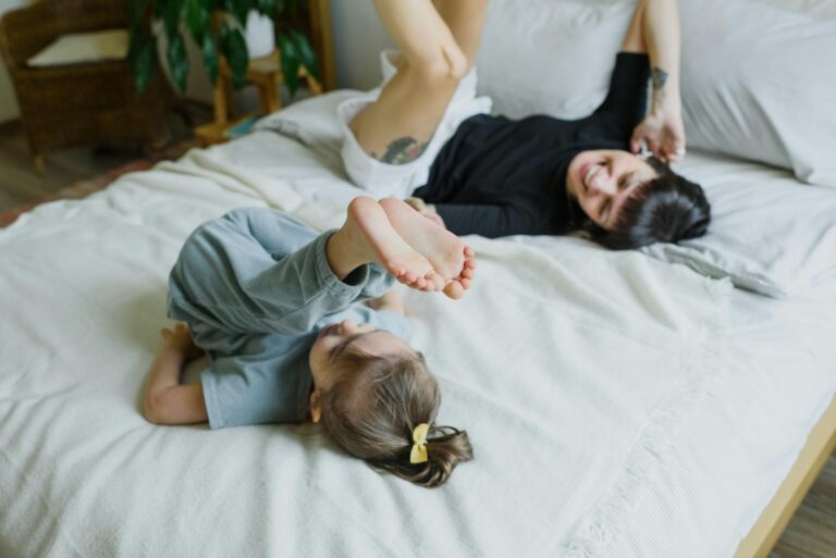 A joyful mother and daughter playing together on a bed, capturing a happy family moment.
