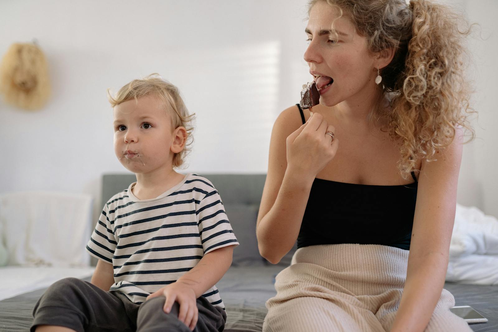 Woman and child sitting together enjoying ice cream on a sunny day indoors.