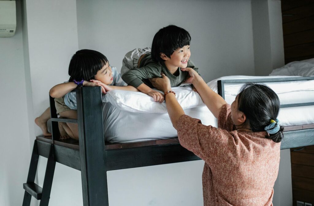 Joyful family moment as a grandmother interacts with children on a bunk bed in a cozy bedroom.