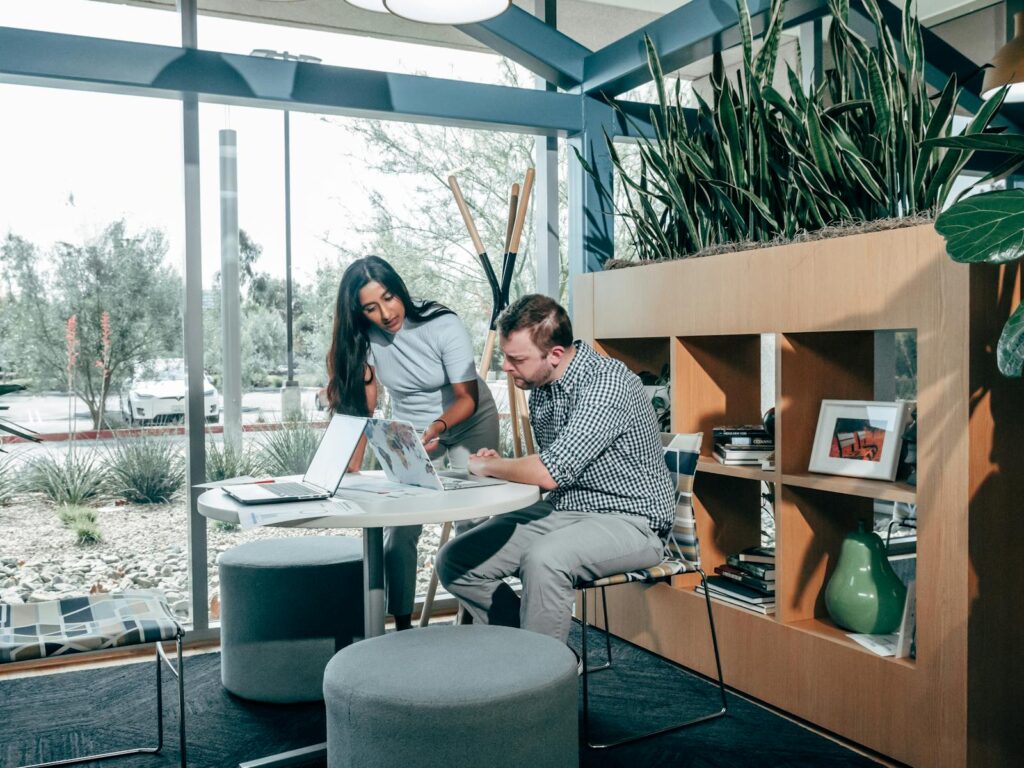 Two colleagues engaging in a project meeting in a modern office space with natural light.