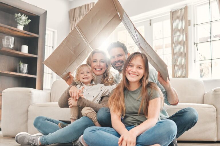 family smiling under a cardboard box