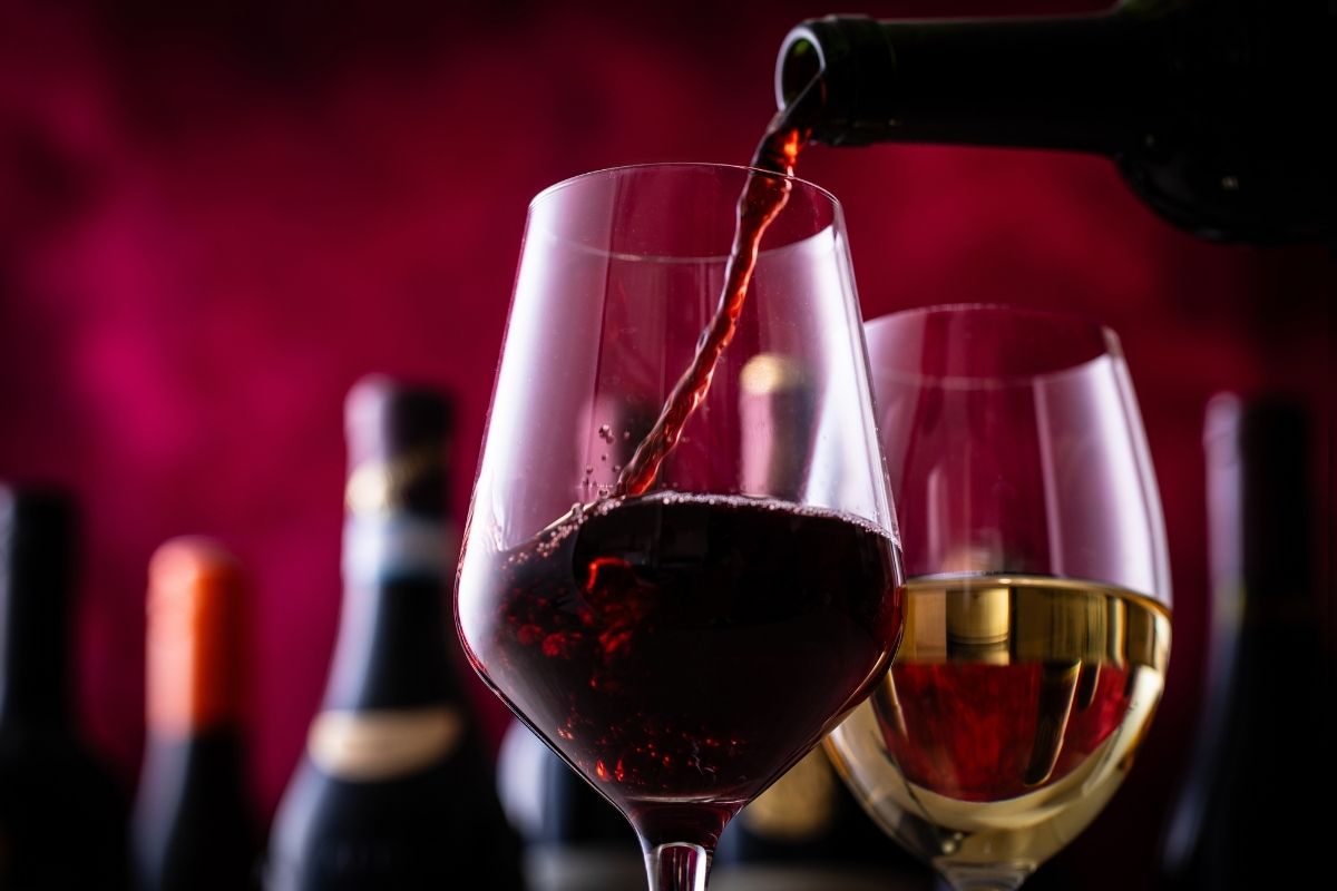 a glass of red wine and white wine behind it