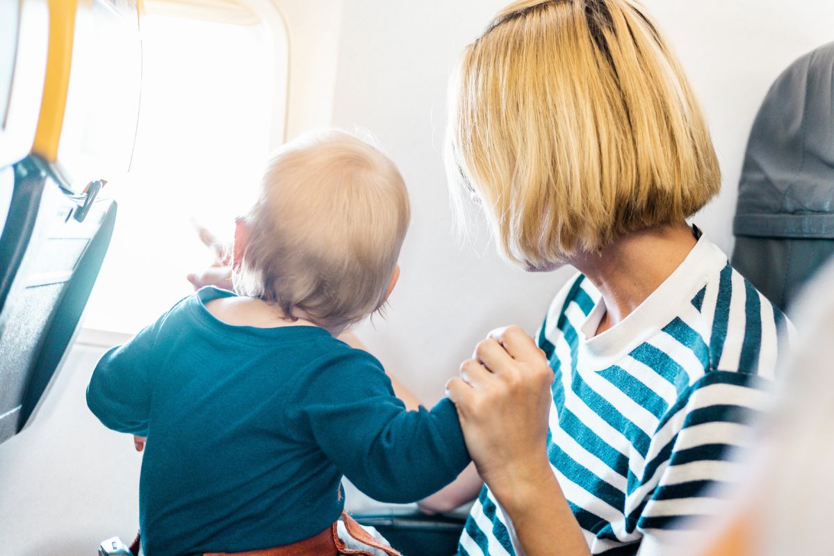 mom looking out the window on a plane with her toddler