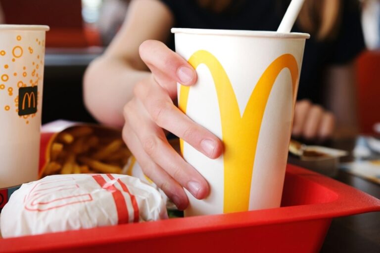 woman holding a mcdonalds cup on a tray with mcdonalds food