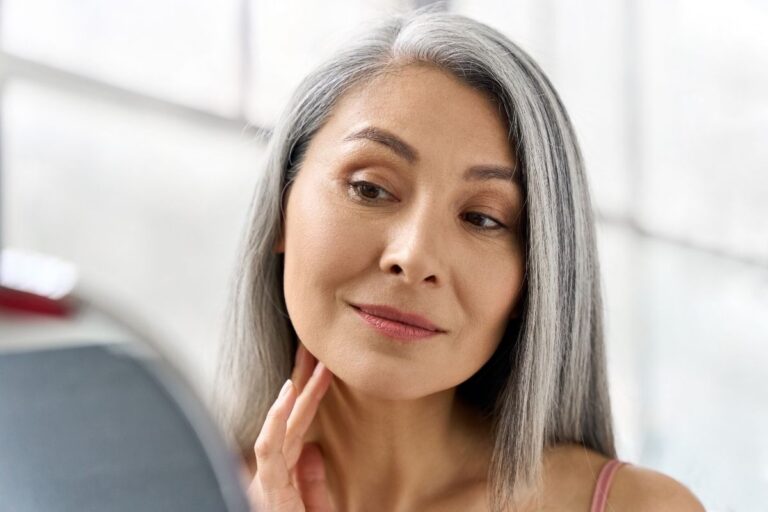 woman with grey hair looking in the mirror