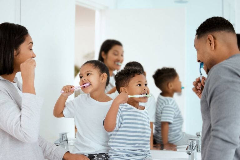 Family all brushing their teeth in the mirror