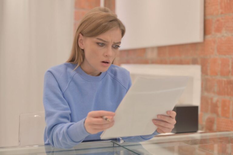 woman in an office reading a piece of paper shocked