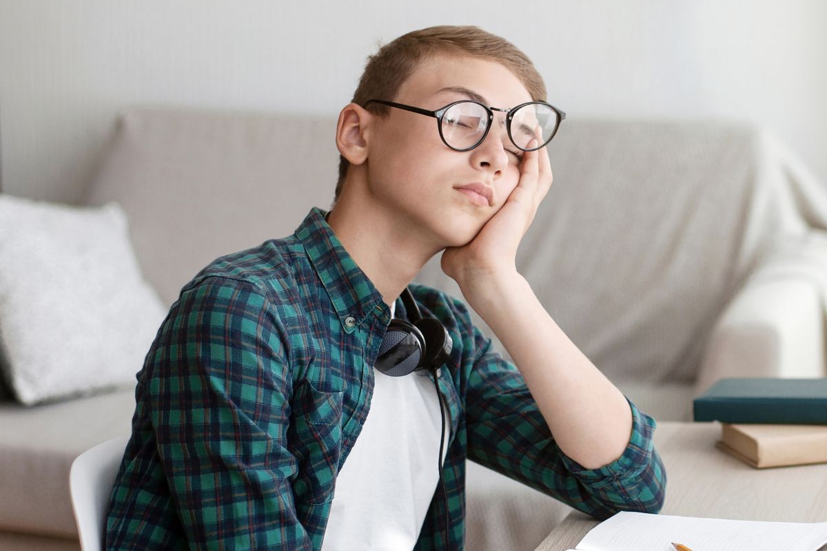 Boy tired wearing glasses at a desk