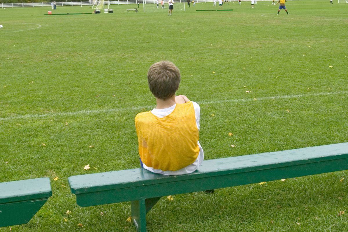 Child sitting on a bench side of the field