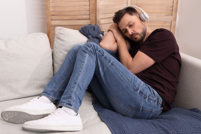 Man looking upset on the couch listening to music
