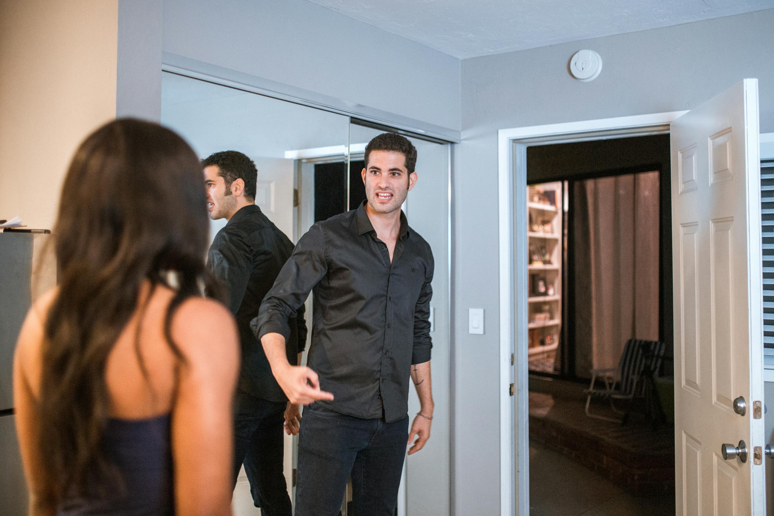 A couple having an intense discussion in a contemporary living room setting with reflections.