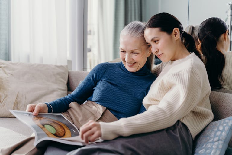 A mother and daughter sharing a joyful moment together on a comfortable couch indoors.
