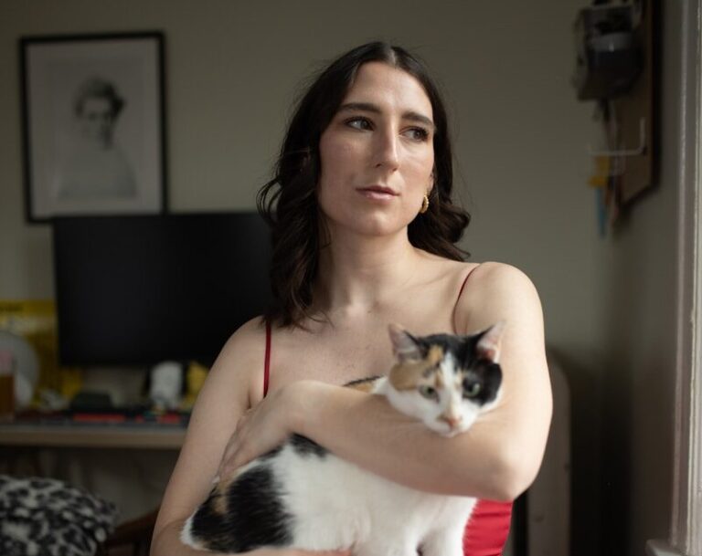 A woman in red holds a cat.