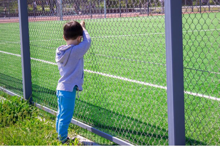 boy alone looking at a sports field