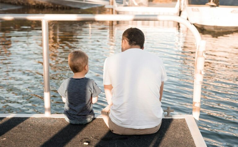 man and boy sitting on dock