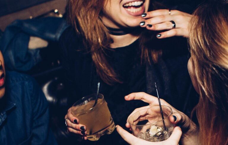 two women talking while holding drinking glasses