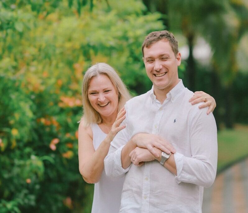 Couple laughing together outdoors with lush greenery