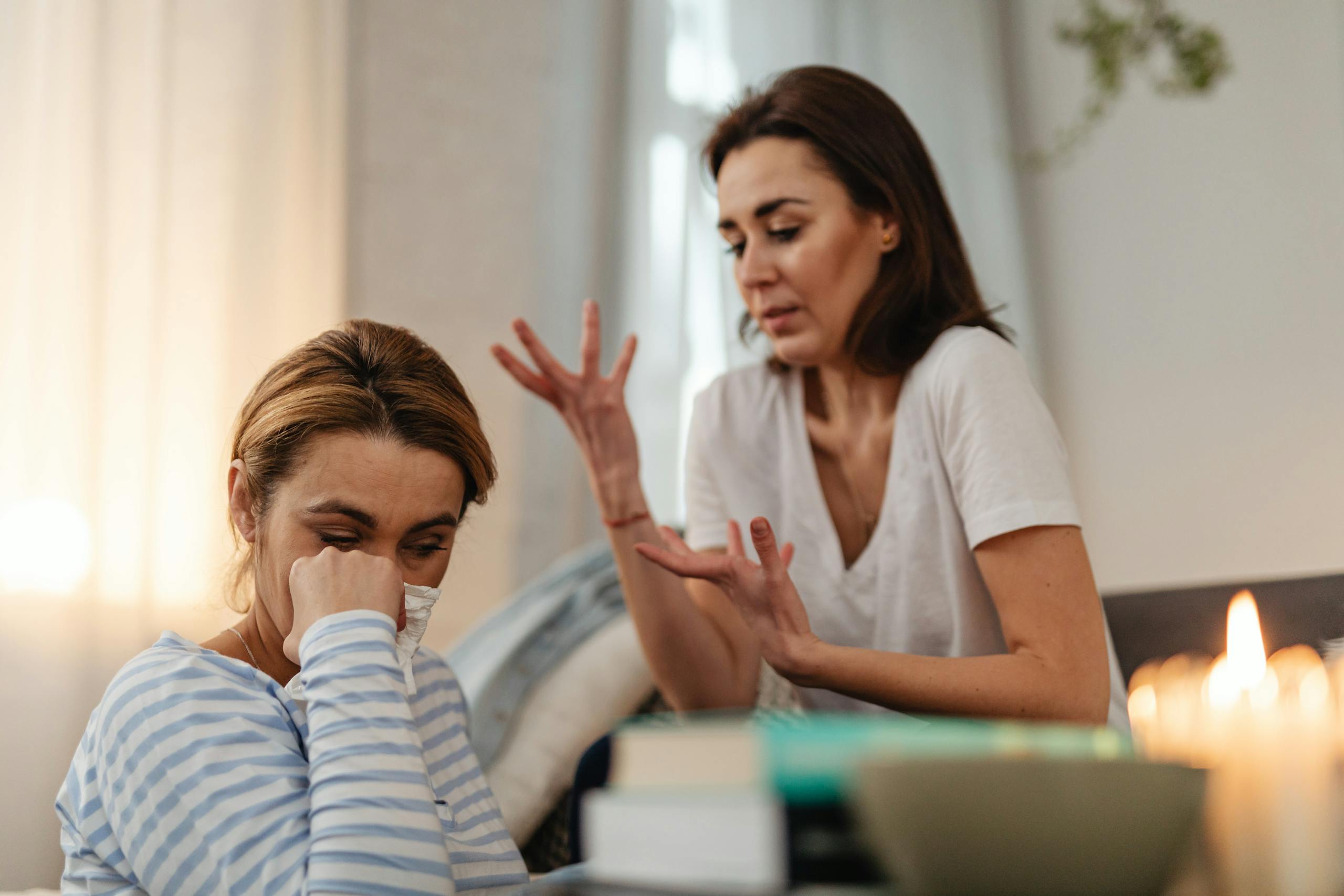 Two women engage in an emotional conversation indoors, addressing issues and stress.