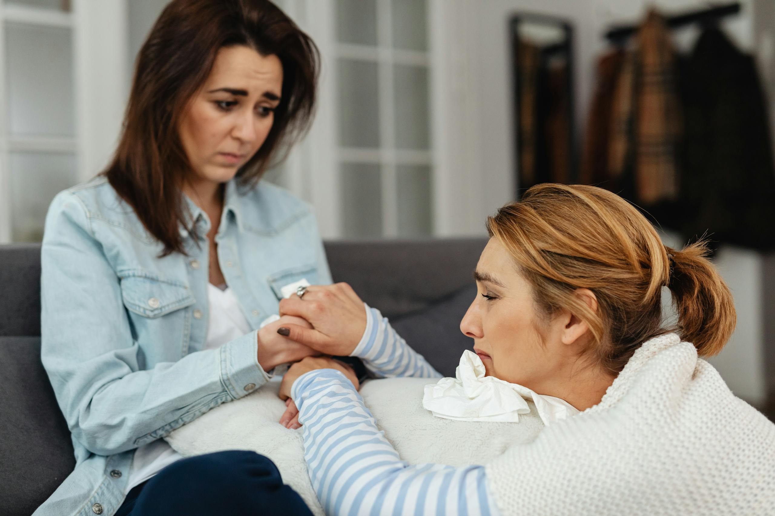 Two women sharing a comforting moment indoors, expressing support and empathy.