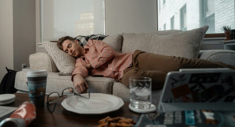 a woman laying on a couch with a plate of food
