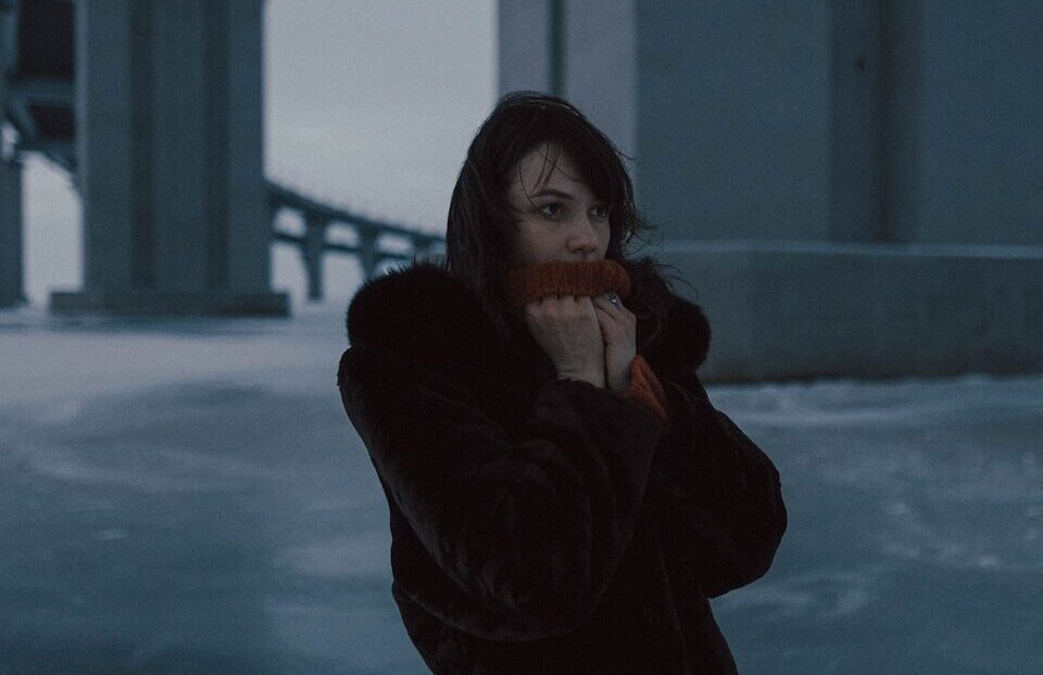 woman in black coat standing on snow covered ground