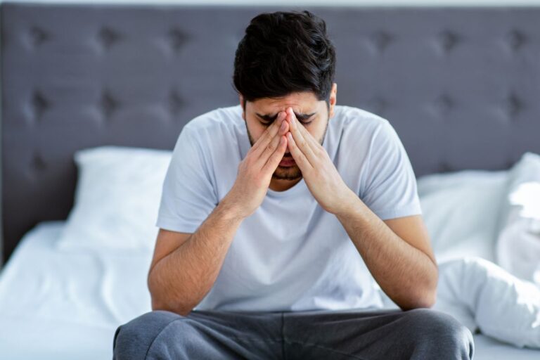 man upset sitting on his bed