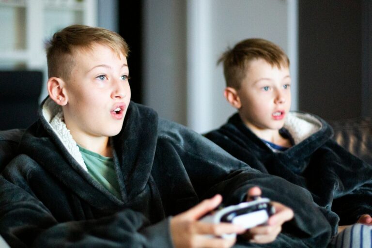two young boys sitting on a couch playing a video game