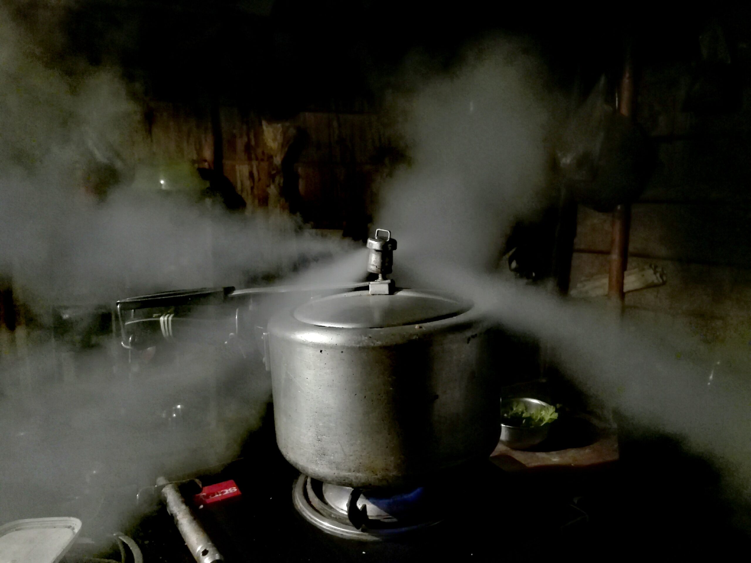 A pressure cooker releasing steam from its lid on a stove