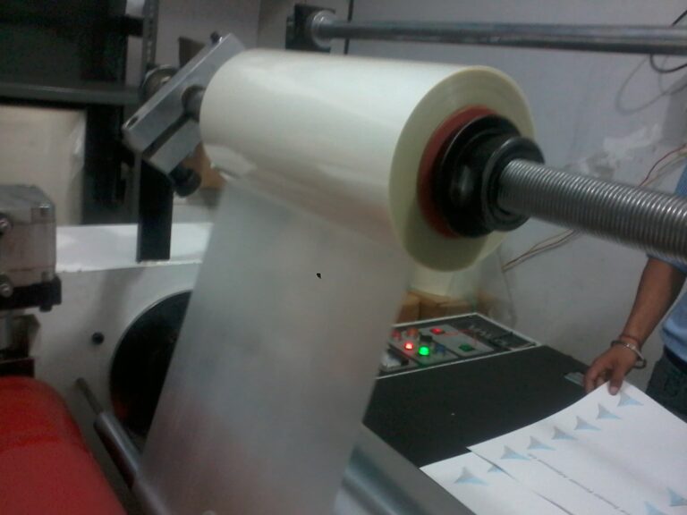 A desktop thermal laminator feeding a sheet of paper sealed in a clear plastic pouch