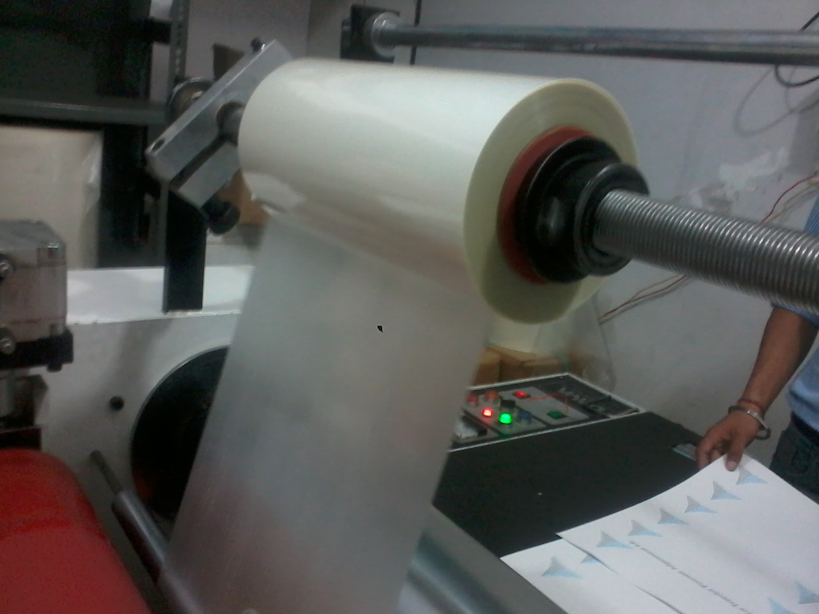 A desktop thermal laminator feeding a sheet of paper sealed in a clear plastic pouch