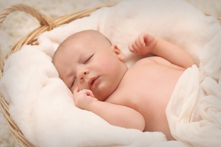 A newborn baby sleeping wrapped in a blanket inside a woven basket